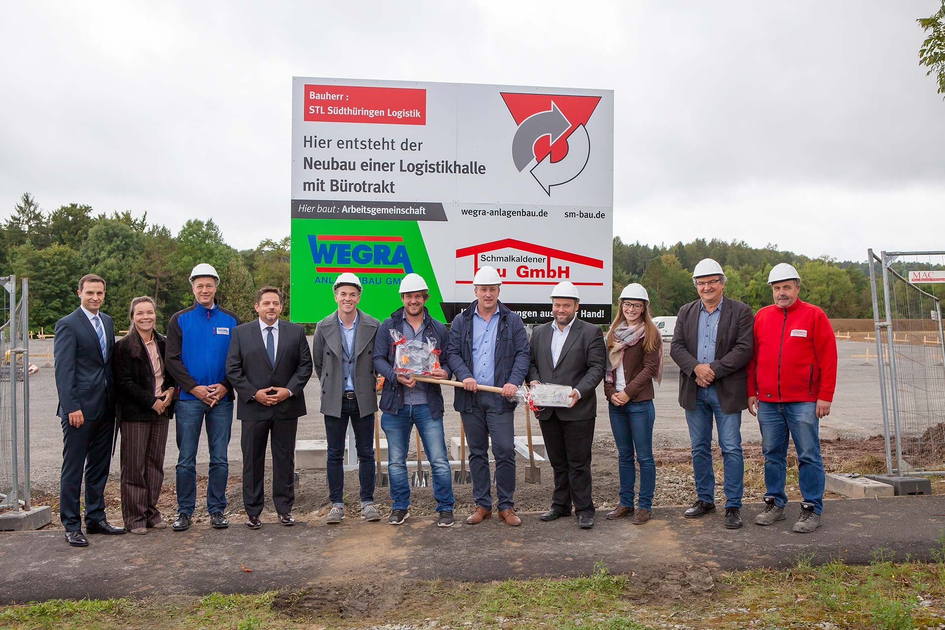 Fabian (5. v. l.), Christopher und André Heimrich, Meiningens Bürgermeister Fabian Giesder (v. l.) sowie u. a. Vertreter der WEGRA Anlagenbau GmbH und Schmalkaldener Bau GmbH begehen den offiziellen Spatenstich zum Neubau der STL-Logistikhalle